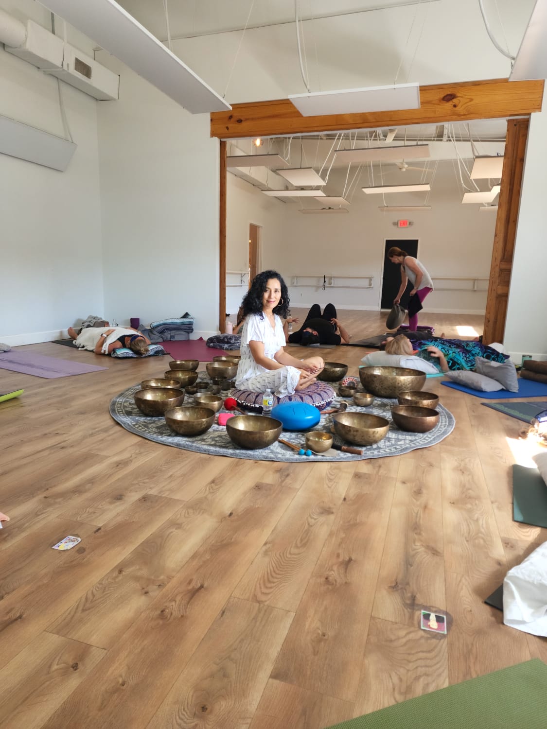 Adwiti seated among the singing bowls at the close of a sound bath.