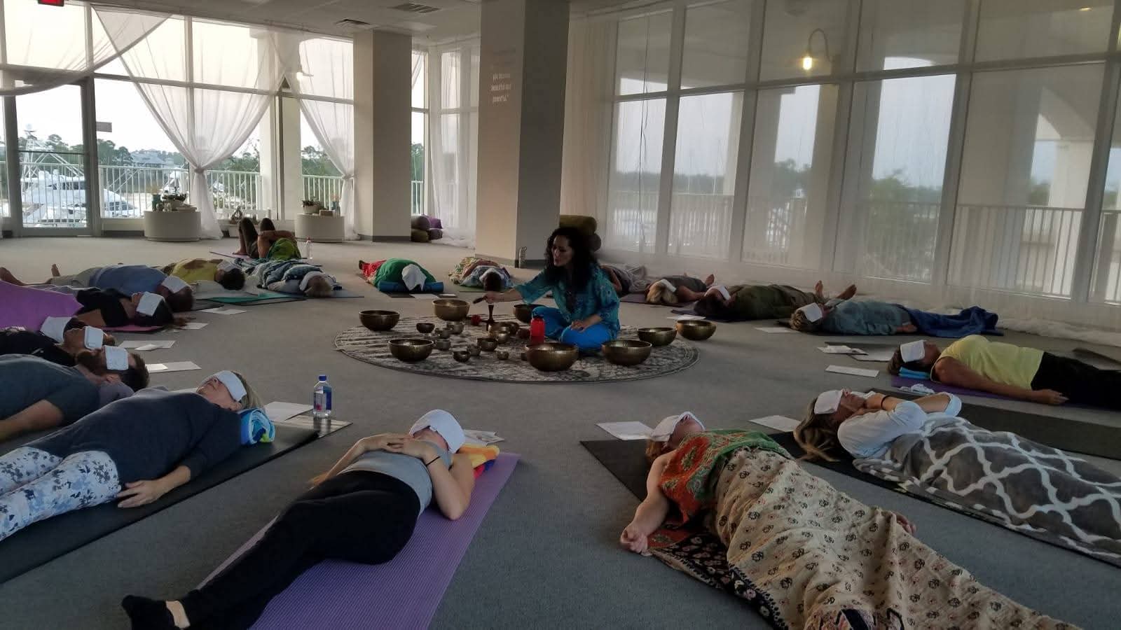 A room of people resting on mats during a Himalayan sound bath led by Adwiti, with singing bowls arranged in a circle.