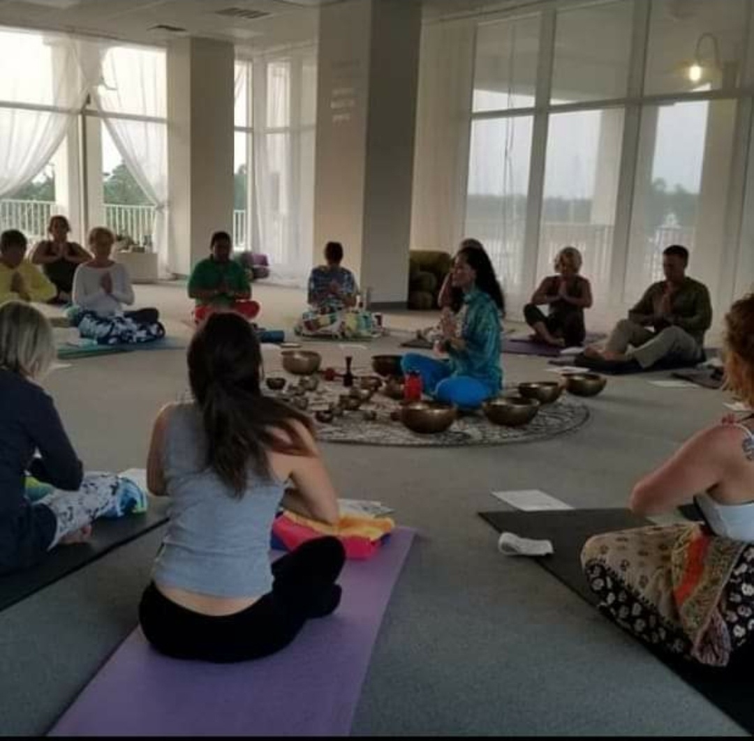 The group seated in a circle with hands at the heart, closing a session together.